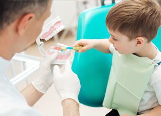 Little boy practicing tooth brushing on model