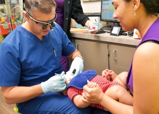 Dentist examining infant with mother.