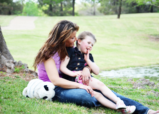 Mother holding daughter in lap outdoors