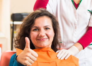 Woman in dental chair giving thumbs up