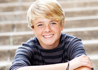 Young boy smiling and sitting on steps